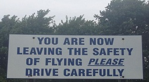Sign stating "You are now leaving the safety of flight, PLEASE drive carefully